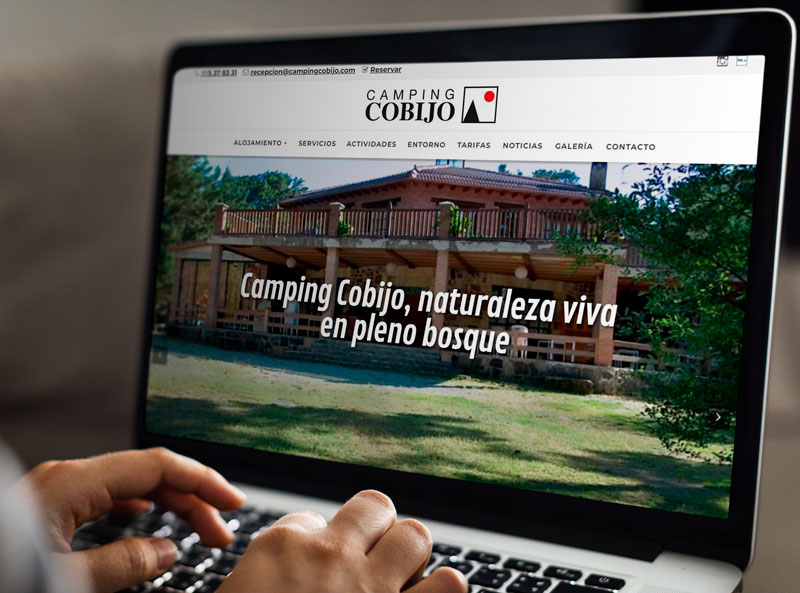 Persona en ordenador portátil viendo la nueva web del Camping Cobijo